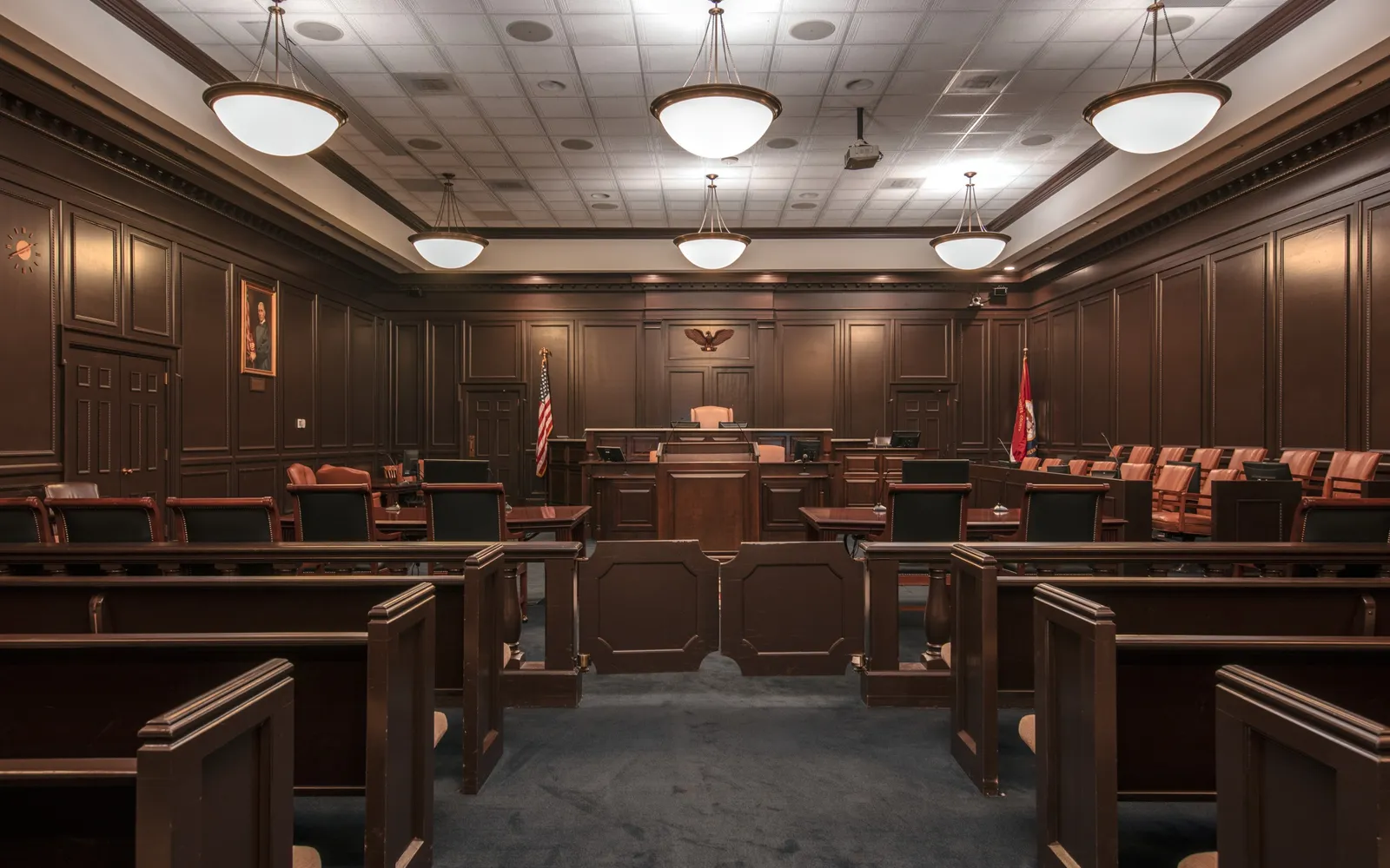 A wood panelled federal courtroom with the judge's bench, jury box and counsel tables