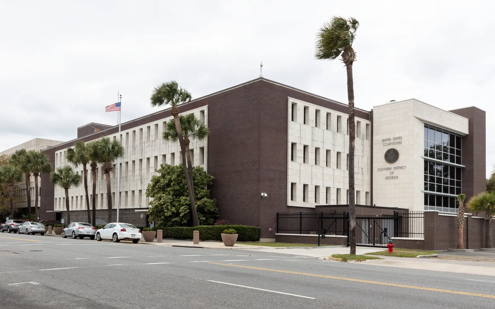 The brick and stone federal courthouse in Brunswick, Georgia, marked United States Courthouse, Southern District of Georgia, with palm trees along the street