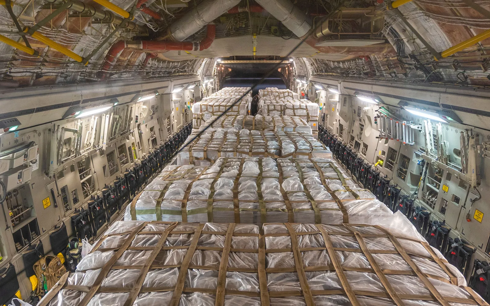 Rows of shrink wrapped pallets of infant formula strapped down in the cargo hold of a C-17 military plane