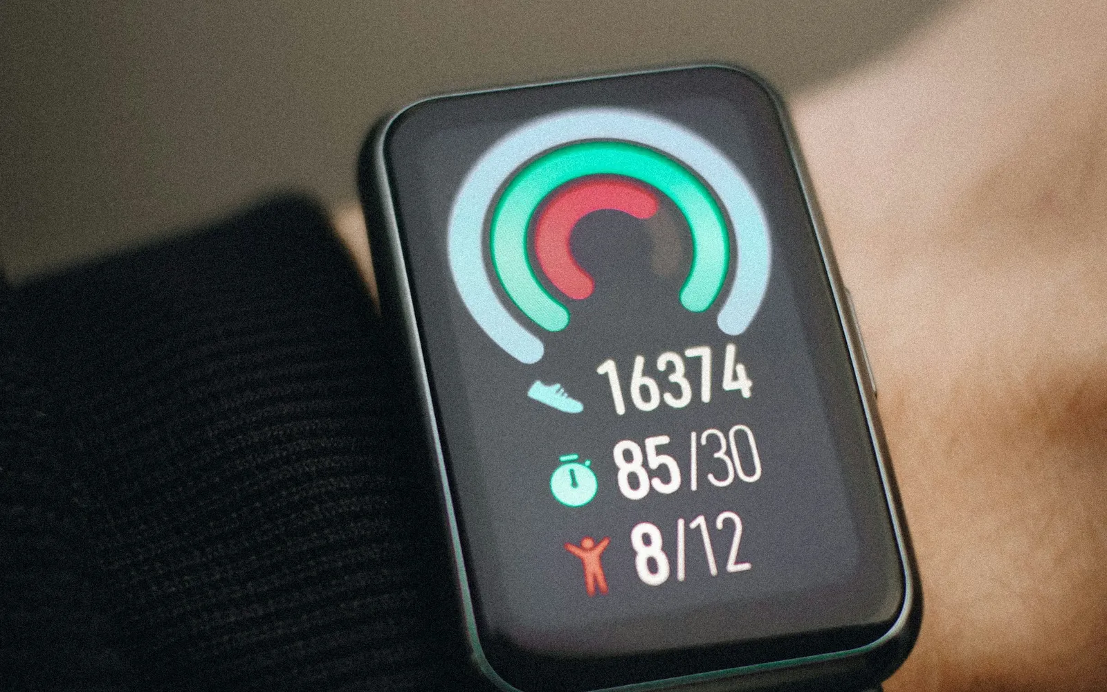 Close-up of a fitness band on a wrist showing steps, heart rate and activity rings