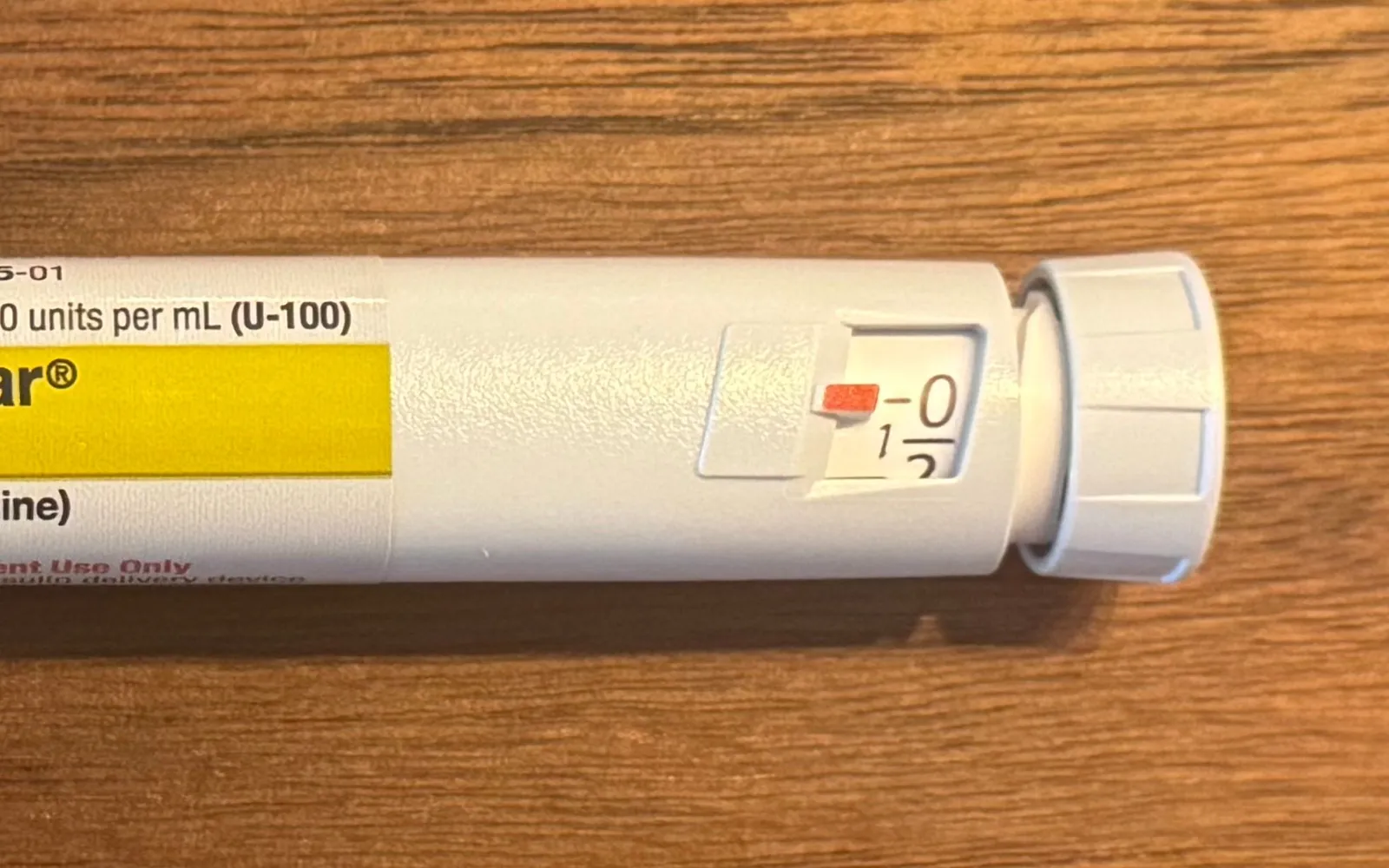 Close up of the dose dial on a white Lilly KwikPen injection pen lying on a wooden table