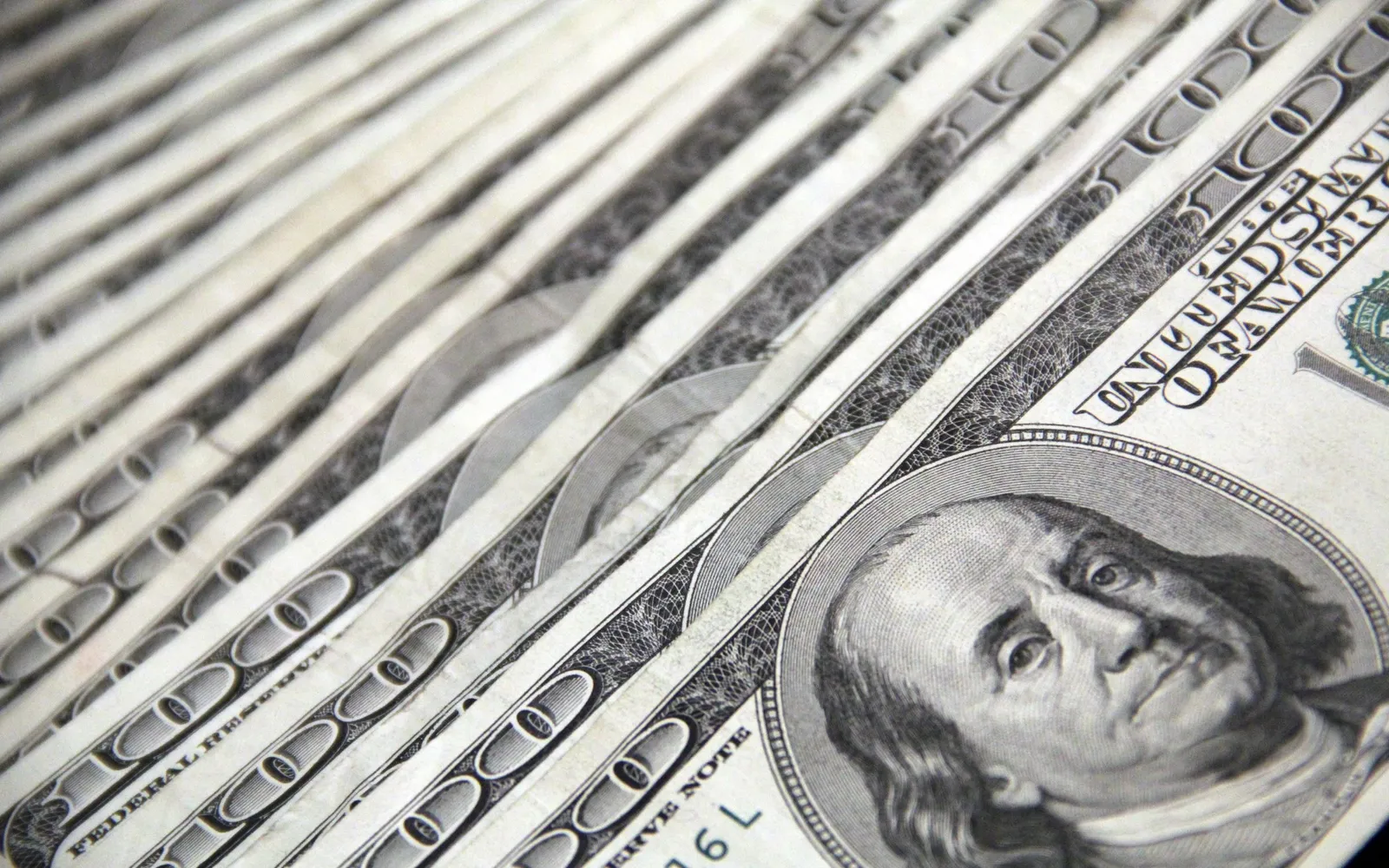 A fan of US hundred dollar bills with Benjamin Franklin's portrait in close up