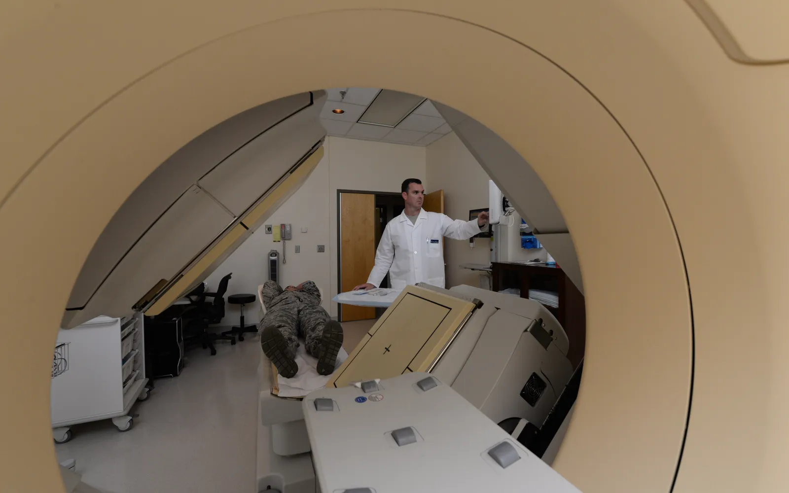 A nuclear medicine technician adjusts a gamma camera scanner, seen through the scanner ring, at Wright-Patterson Air Force Base Medical Center